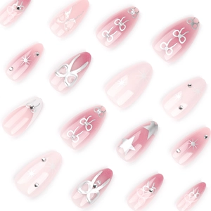 French almond press-on nails with pink gradient, silver bows, and sparkling stars