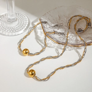 Detailed view of dual-tone twisted chain necklace and bracelet set with gold bead charms