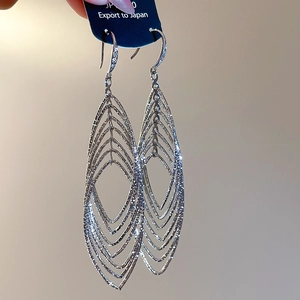 Détail macro de boucles d'oreilles argentées multicouches avec texture zircone brillante