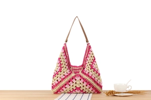 Detail of woven tote bag featuring pink geometric floral patterns and brown leather strap