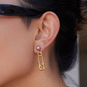 Gros plan de boucles d'oreilles épingle de nourrice bicolores or 18K et argent portées