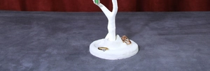 White tree-shaped jewelry organizer stand with round base tray on red fabric