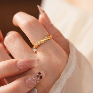 Close-up of a vintage golden twist ring with inlaid diamonds on a finger