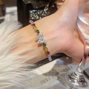 Dettaglio del bracciale farfalla d'argento con pietre preziose colorate sul polso