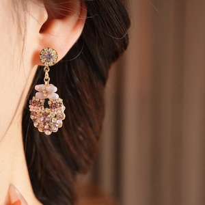 Close-up of vintage gold earrings with pink crystals and beads on a model's ear