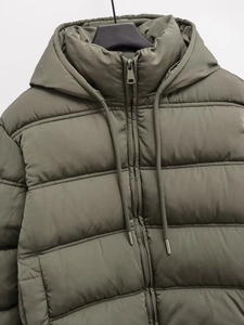 Detail of dark olive green puffer jacket with metal zipper and drawstring hood