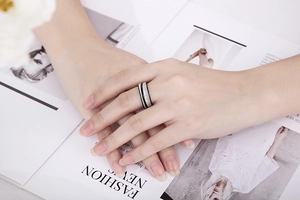 Minimalist silver and black stainless steel ring with a brushed texture on a hand