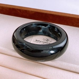 Macro view of black resin bangle with white marble texture inside a wooden jewelry box