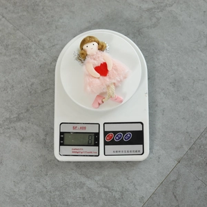 Close-up of pink plush Christmas angel doll weight measurement showing 8 grams