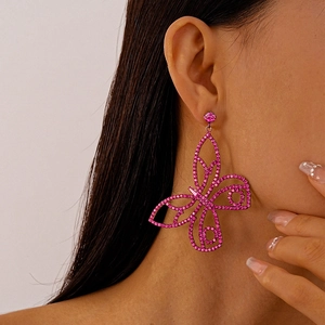 Close-up of pink hollow butterfly drop earrings with sparkling rhinestones on model