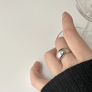 Close-up of minimalist silver dome ring with polished mirror finish on model's hand