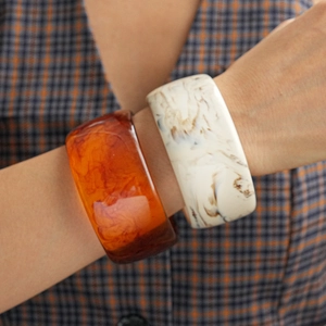 Detail of amber and cream marbled resin bangles showing textured finish on wrist