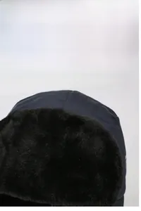 Close-up of windproof winter hat featuring thick black plush faux fur lining and earflaps