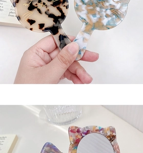 Detail view of cat-shaped handheld makeup mirrors in tortoiseshell and mosaic patterns