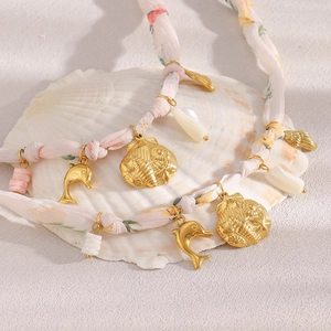 Detail of 18K gold dolphin and shell pendants on a pink floral ribbon necklace