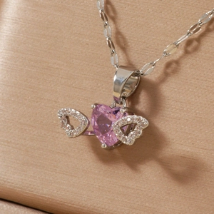 Silver heart necklace with pink zircon and wings on champagne silk background