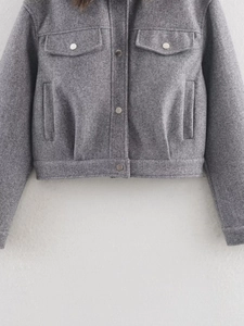 Detail showing the thick grey wool blend fabric texture and metal buttons on the jacket