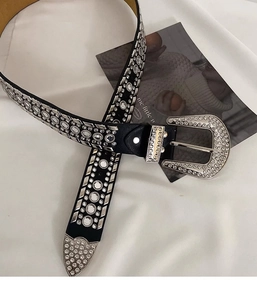 Detail of a punk style black leather belt featuring silver rivets and sparkling rhinestones