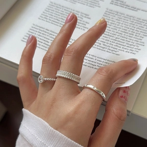 Close-up of stacked silver rings with cubic zirconia on a minimalist magazine background