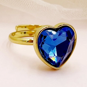 Détail macro d'une bague dorée réglable avec une grande pierre précieuse bleue en forme de cœur