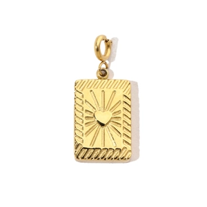 Detail of a vintage gold rectangular pendant with a heart motif and sunburst engraving