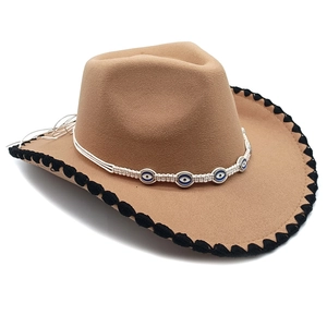 Detail of light brown wool fedora hat featuring woven evil eye band and stitched edge