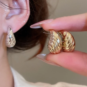 Detailed view of spiral texture metal stud earrings in gold and silver plated finishes