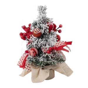 Miniature flocked Christmas tree with red berries and polka dot ribbon on linen base