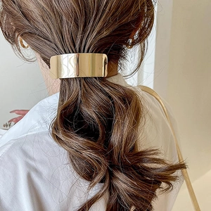 Close-up of a minimalist gold ponytail buckle clip worn by a model in a sleek style