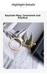 Detail of black leather key pouch with golden ring, white stitching and metal chain