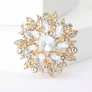Macro detail of a sunflower brooch with gold plating and faceted crystal center