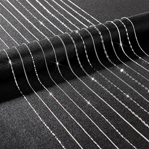 Macro view of various silver chain styles including snake and box chains on black background