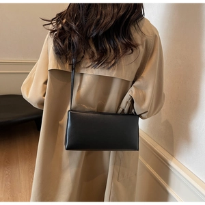 Minimalist black leather baguette bag styled with a trench coat for a chic winter look