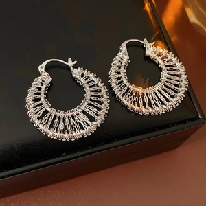 Vue détaillée de boucles d'oreilles créoles tressées argentées sur cuir noir
