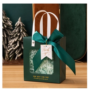 Detail of dark green gift bag featuring a transparent window, ribbon bow, and thank you tag