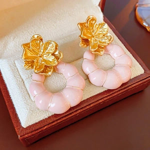 Détail de boucles d'oreilles fleurs dorées vintage avec anneaux roses en boîte à bijoux