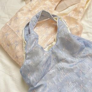 Gros plan sur un tissu en maille bleu clair et rose avec broderie de nœuds délicats