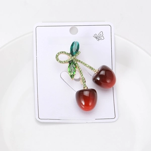 Detailed view of a cherry brooch with red enamel fruit and green crystal leaves
