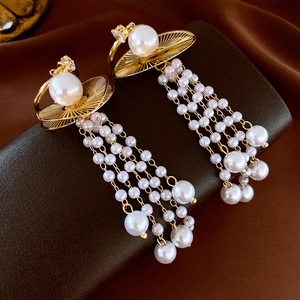 Détails de boucles d'oreilles dorées à pampilles avec perles et zircons brillants