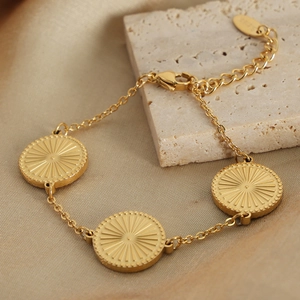 Gold stainless steel bracelet with sunburst engraved round charms on elegant silk backdrop