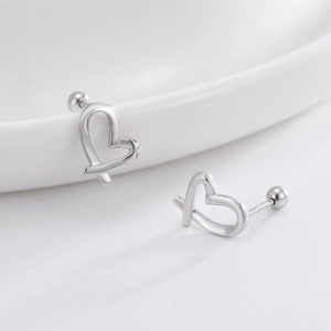 Polished S925 sterling silver hollow heart stud earrings on a white ceramic plate