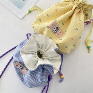 Detailed macro view of checkered canvas drawstring bags with cute animal embroidery