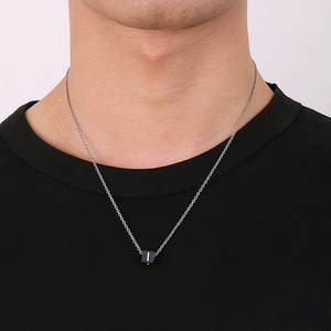 Gros plan d'une chaîne argentée pour homme avec pendentif cube noir sur un t-shirt