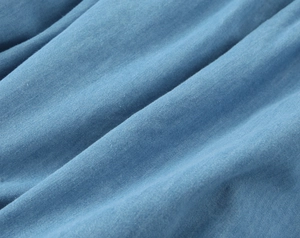 Détail macro du tissu en coton bleu montrant le tissage sergé et les plis souples