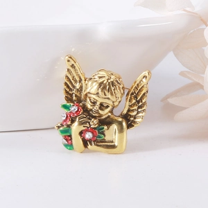 Macro detail of vintage gold angel brooch with green and red enamel flowers and rhinestones