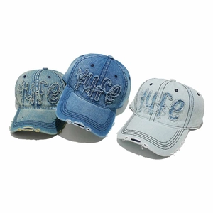 Close-up of distressed denim baseball caps with LIFE embroidery and frayed edges