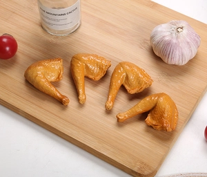 Detailed realistic fake chicken wing food models on a wooden board in a kitchen scene
