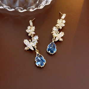 Detail view of drop earrings with blue crystal waterdrops and zirconia butterfly design