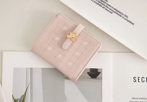 Detailed view of pink floral wallet featuring metal flower buckle and plaid texture