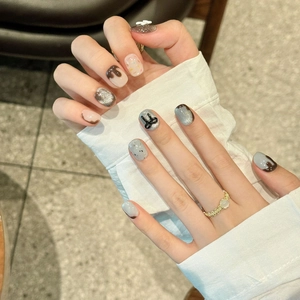 Faux ongles chocolat faits main avec nœuds 3D et paillettes argentées sur mains